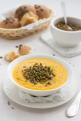 Pumpkin soup with lentils in a white bowl on textiles
