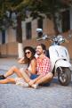 Young couple sitting near white retro scooter