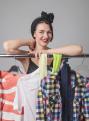 Attractive woman standing near the racks of clothes .