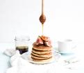 Pancake tower with fresh figs and honey on a rustic plate. White background