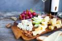 Wine snack set. Glass of red and white wine, grape and various sorts cheese, over rustic wooden background.