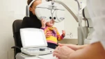 High technology in ophthalmology - optometrist in clinic checking little girl's vision - children's medicine