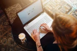 Top view of young female student working on laptop sitting at table