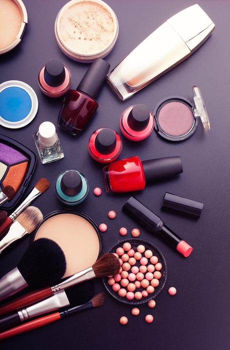 Various makeup products on dark black background with copyspace