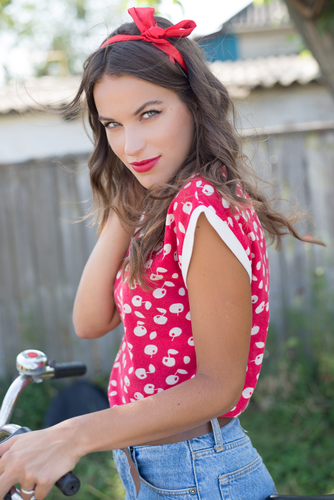 Young beautiful pinup woman cycling in countryside